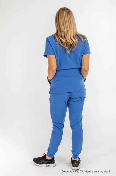 Women's SAYA Jogger Scrub Pant, lady featuring the back of scrub set both hands are inside the scrub top pocket #colour_royal-blue