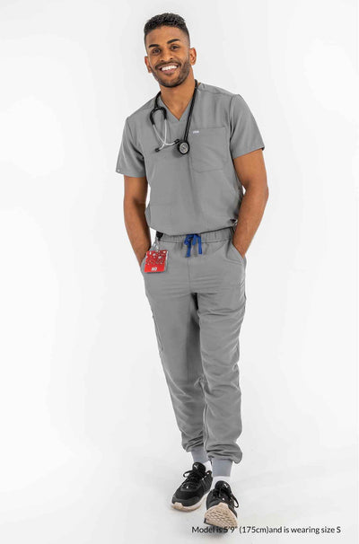Men's AESON Scrub Top, 2 hands of men is inside the pocket, Men has stethoscope  on his neck #colour_grey