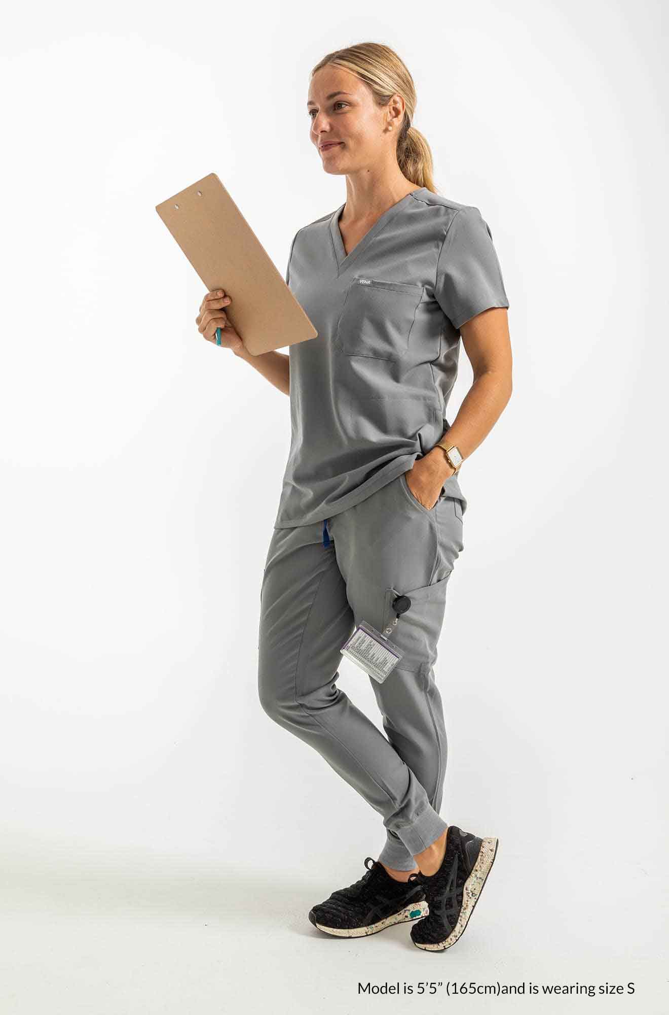 Women's ATRIUM Scrub Top, Lady holding checklist on the right hand and the right hand is inside the right pocket of scrub pant #colour_grey